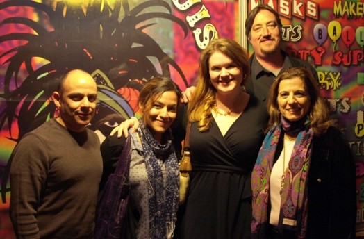 A photo of a group of people standing in front of a colorful wallpaper.
