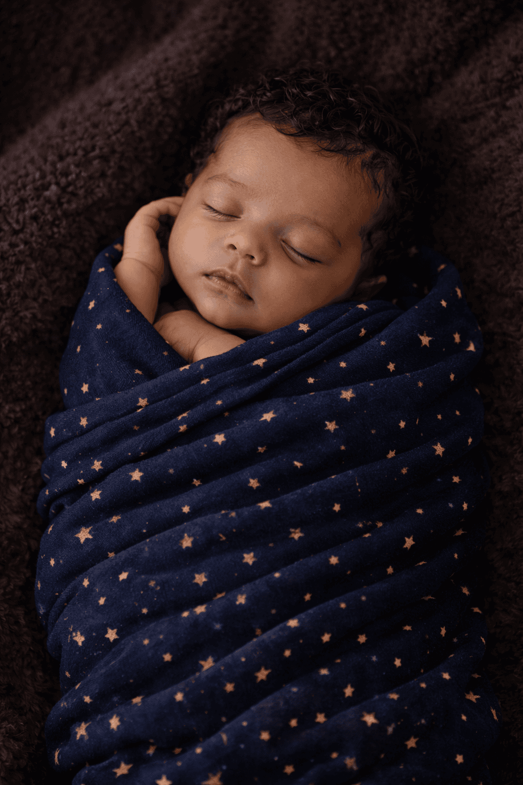 A peaceful newborn baby sleeping soundly wrapped in a soft white blanket, shot from above
