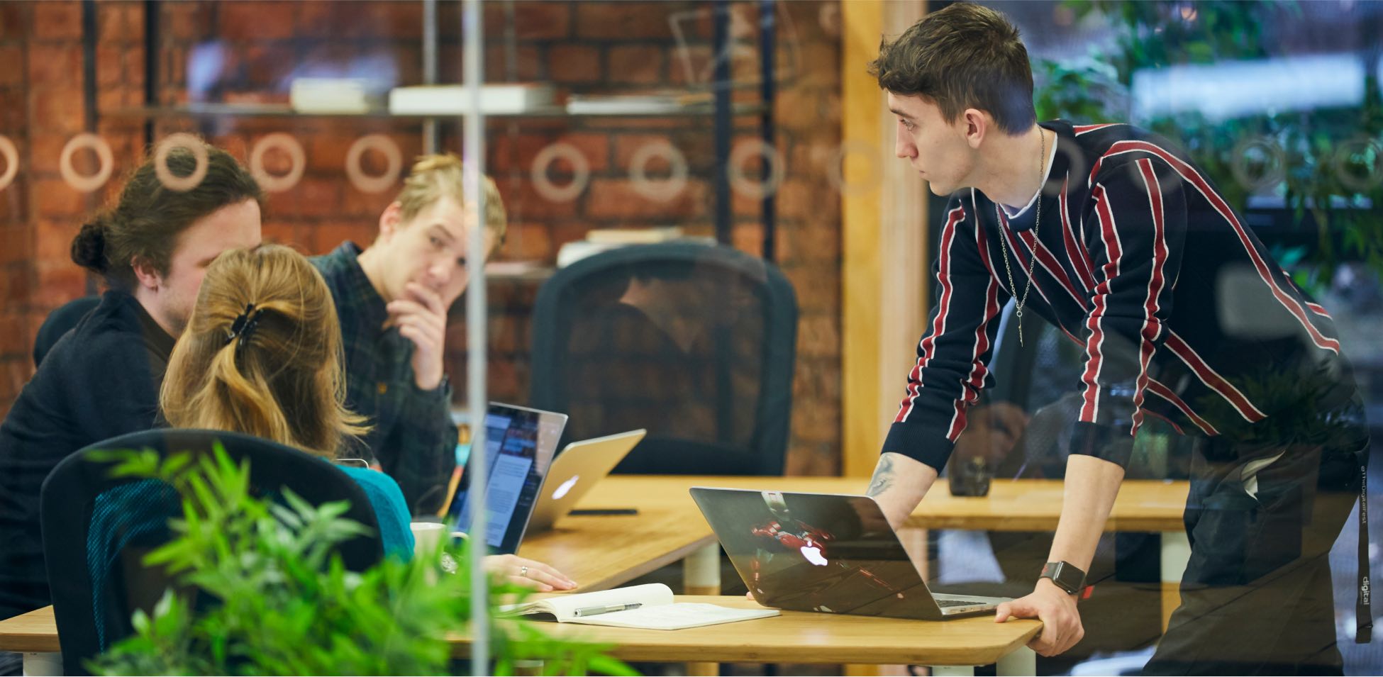 People working on laptops at a wooden table.