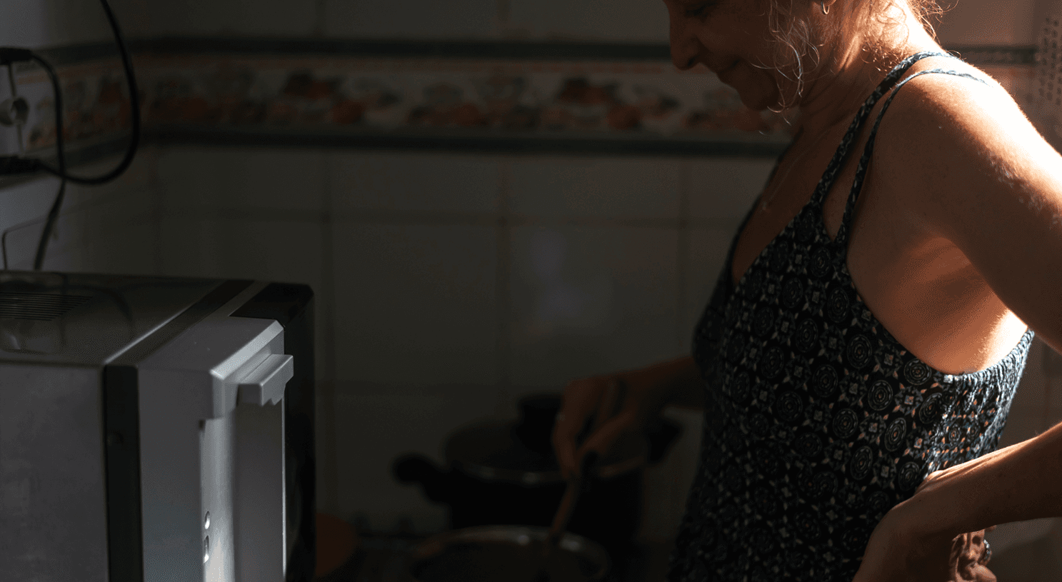 Young caregiver stands at stove stirring sauce in pot