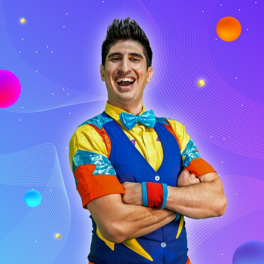 A woman with blonde bob hair in a grey coat and beige turtleneck stands against a neutral backdrop. She has a serious expression, conveying elegance.