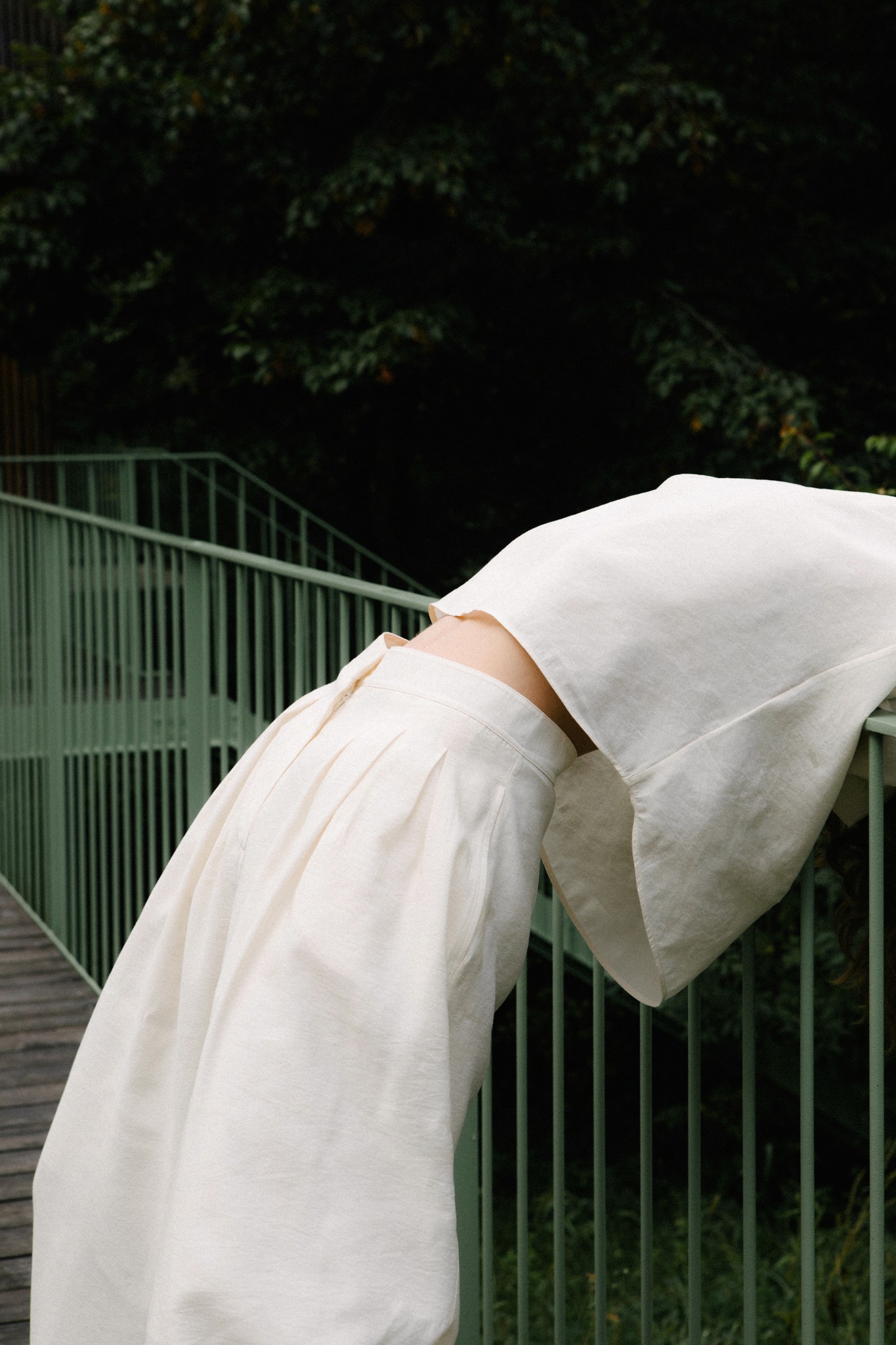 Frau beugt sich über Geländer im Grünen – Herz & Kreislauf