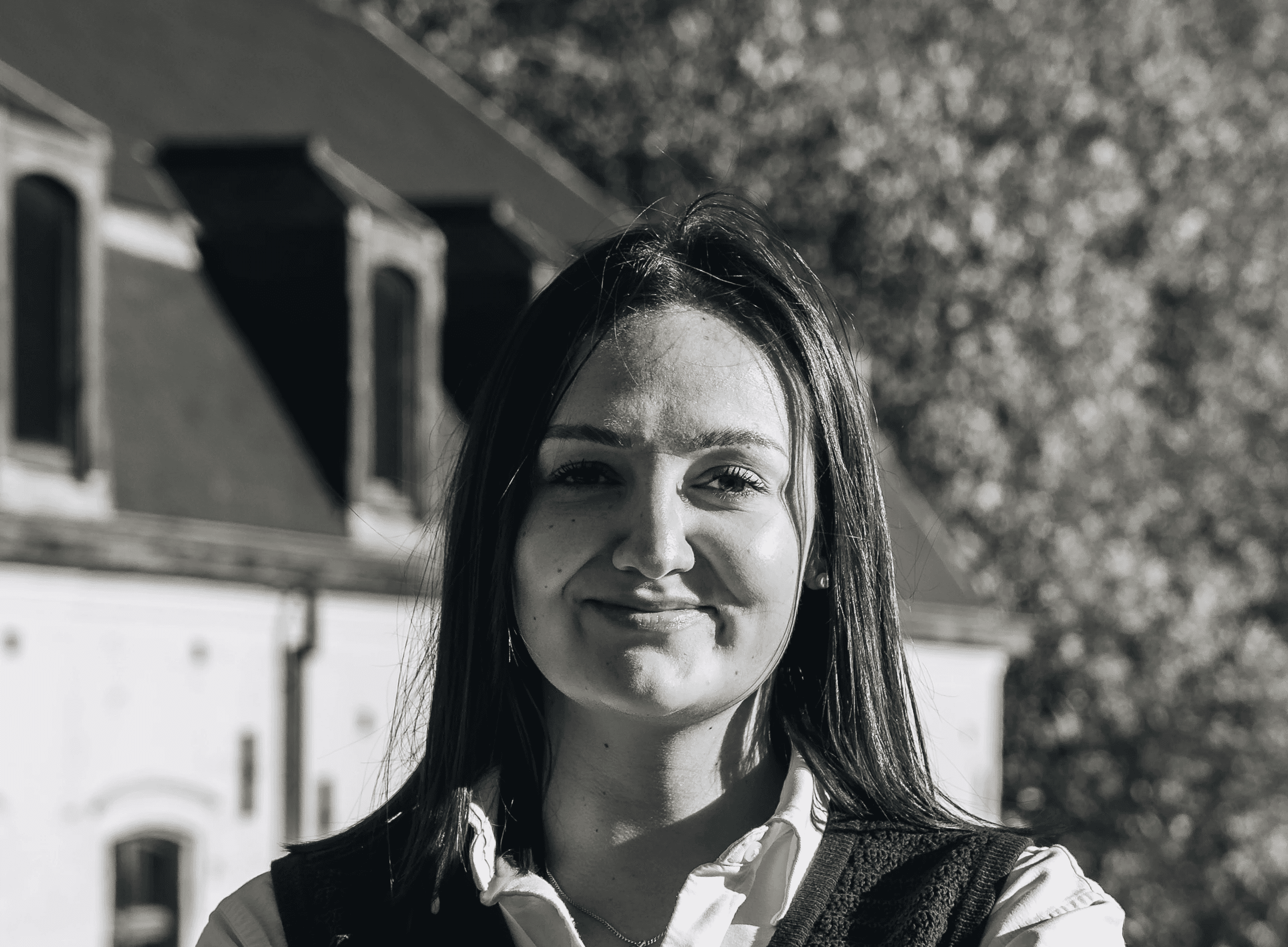 Portrait of a laughing person with curly hair wearing a white shirt