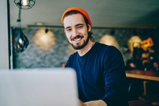 Trendy looking person using laptop from behind during day in cozy, modern home office