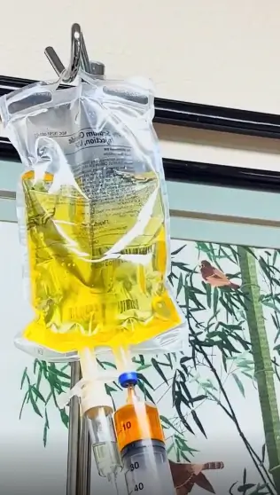 Yellow vitamin IV therapy drip bag on pole.