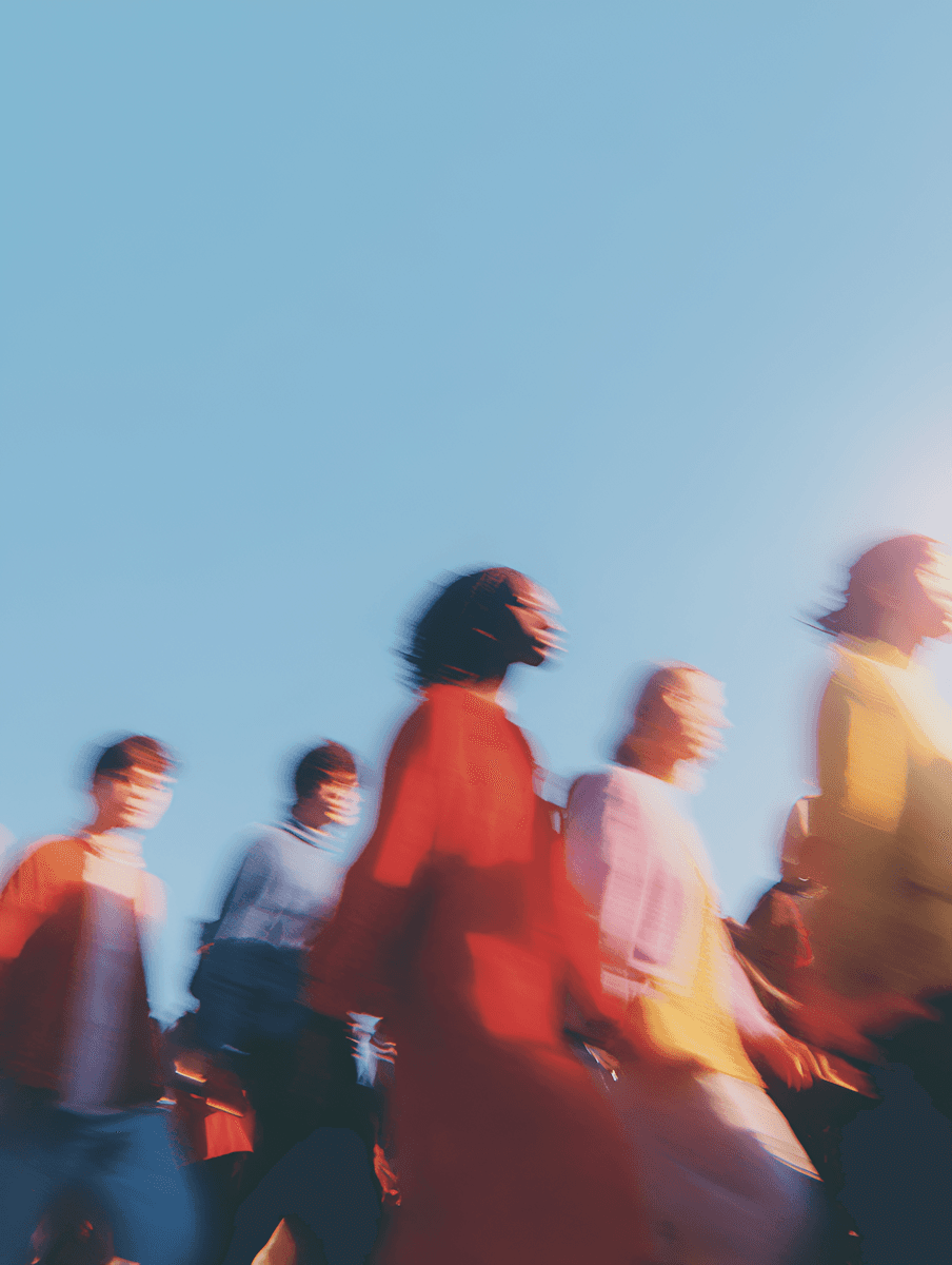 Blurred group of diverse people walking under a clear blue sky.