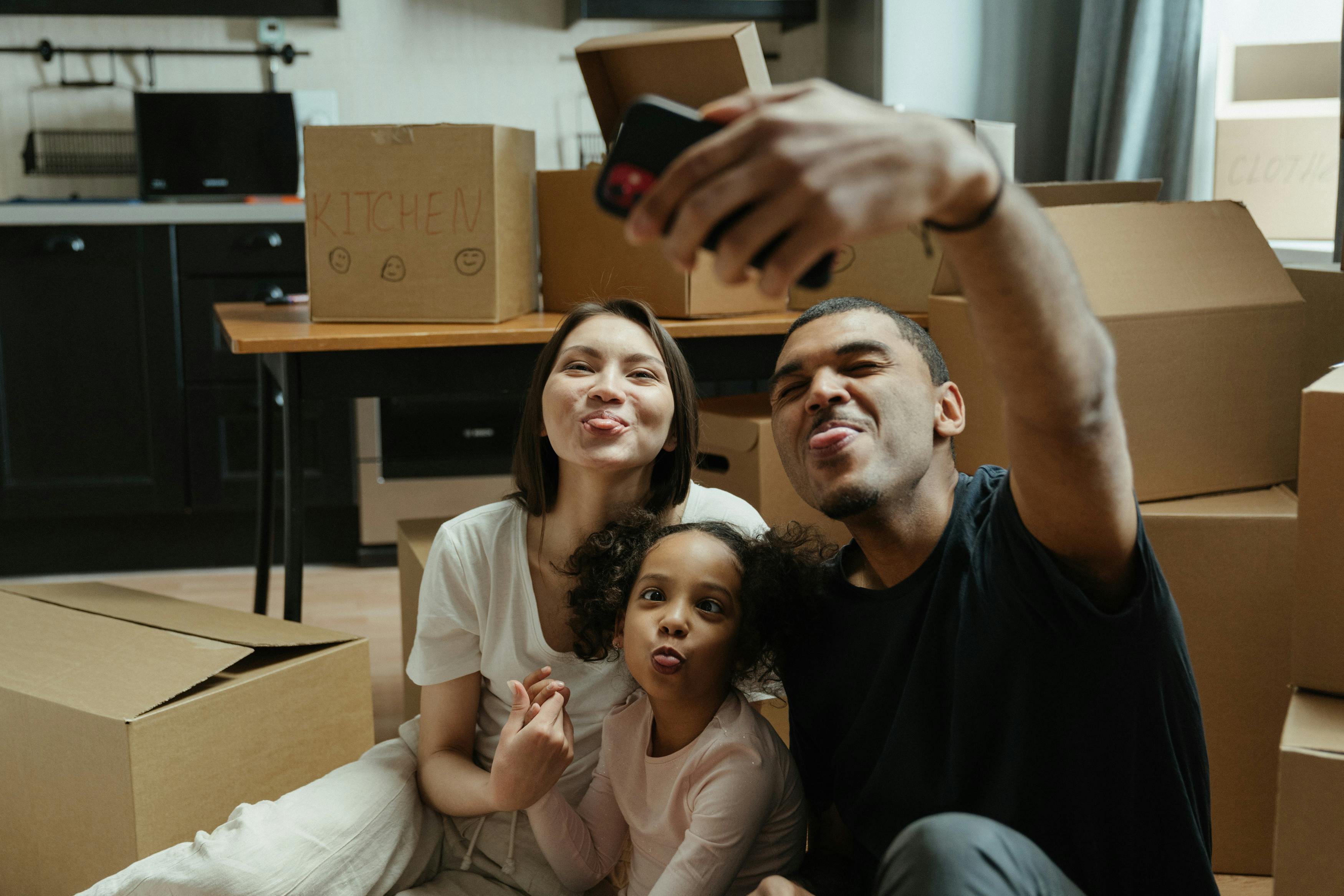 Mixed race family surrounded by boxes taking a selfie