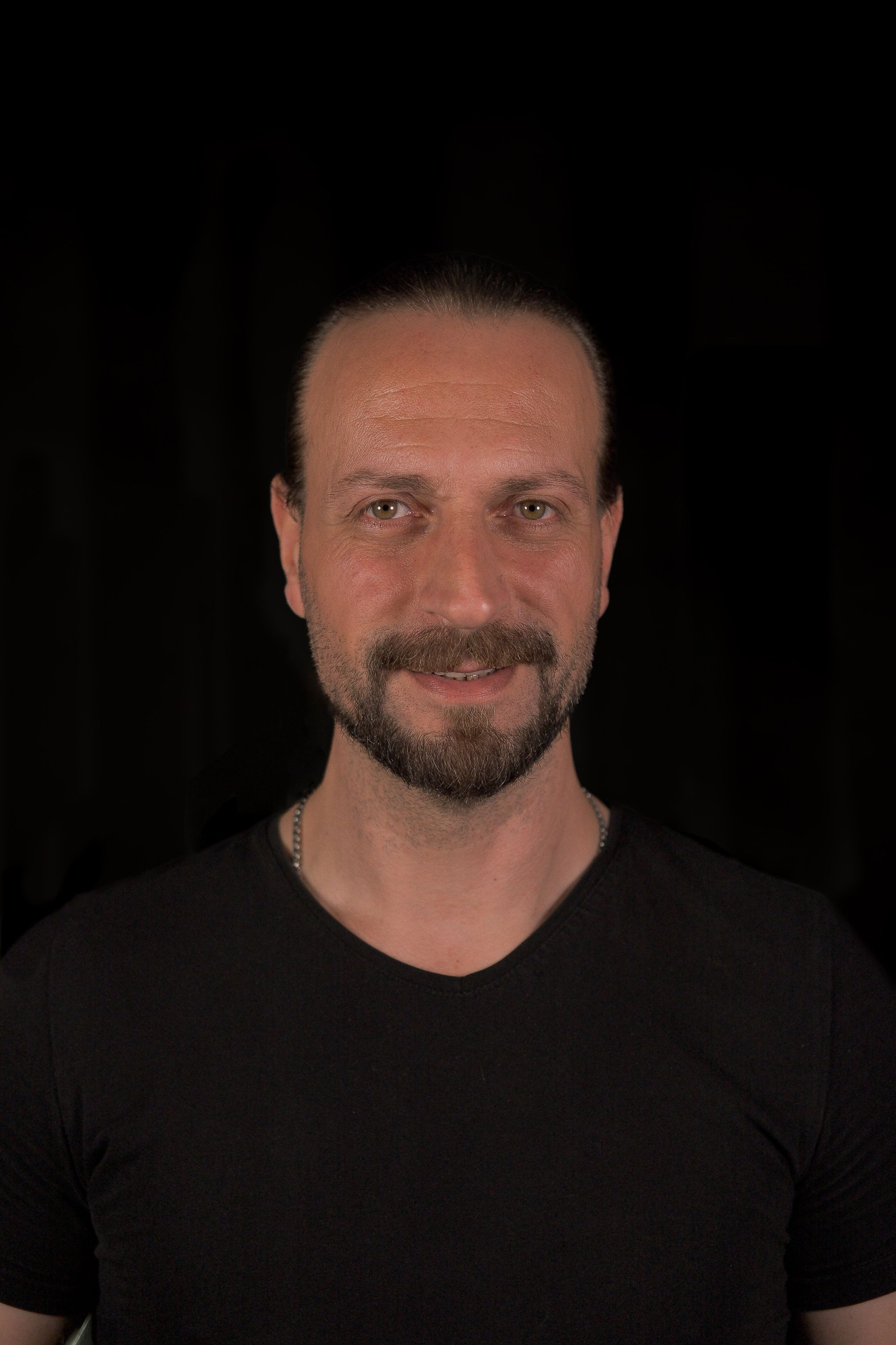 A person with a beard standing in the dark.