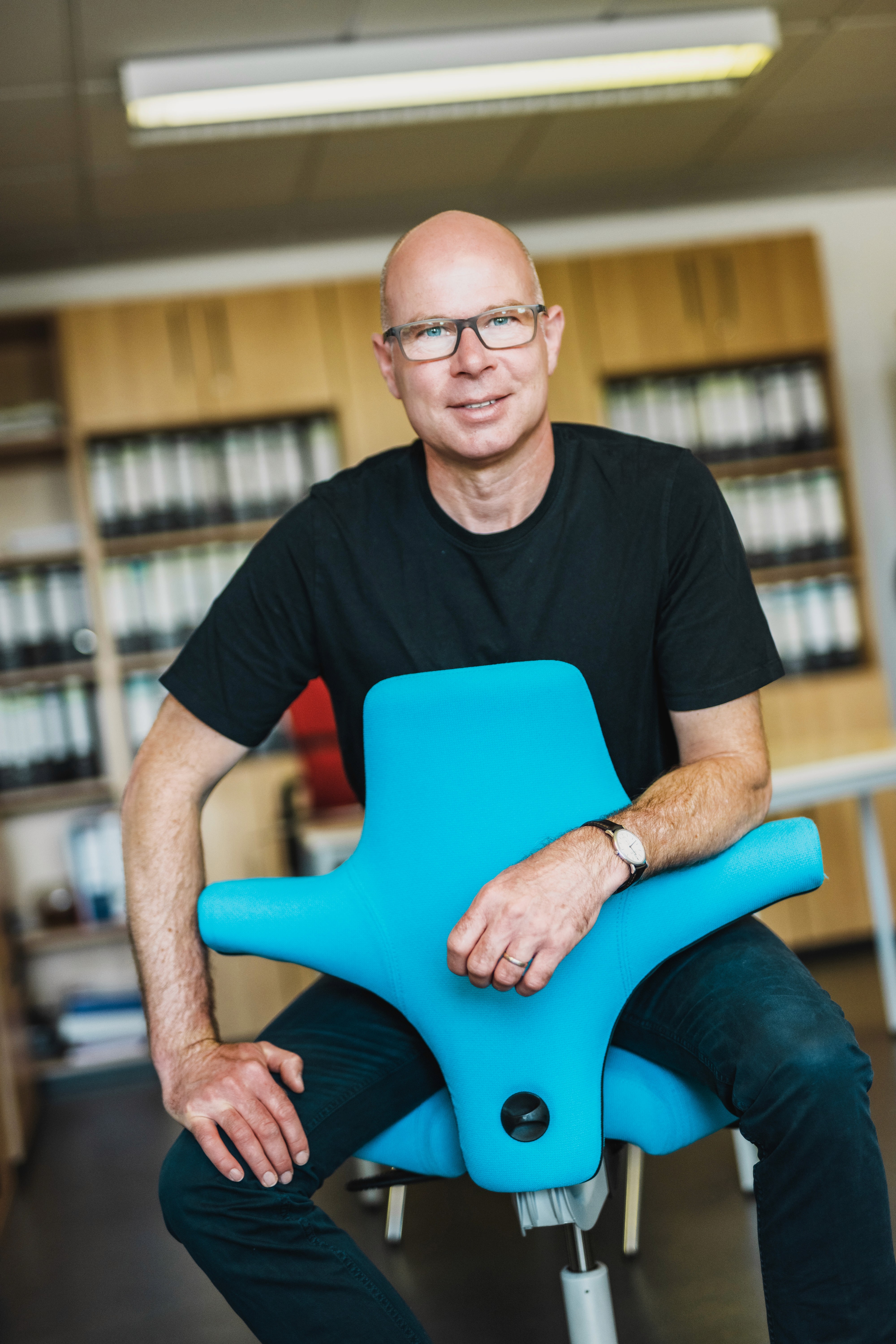 Sven Eichner sitzt auf einem blauem Bürostuhl