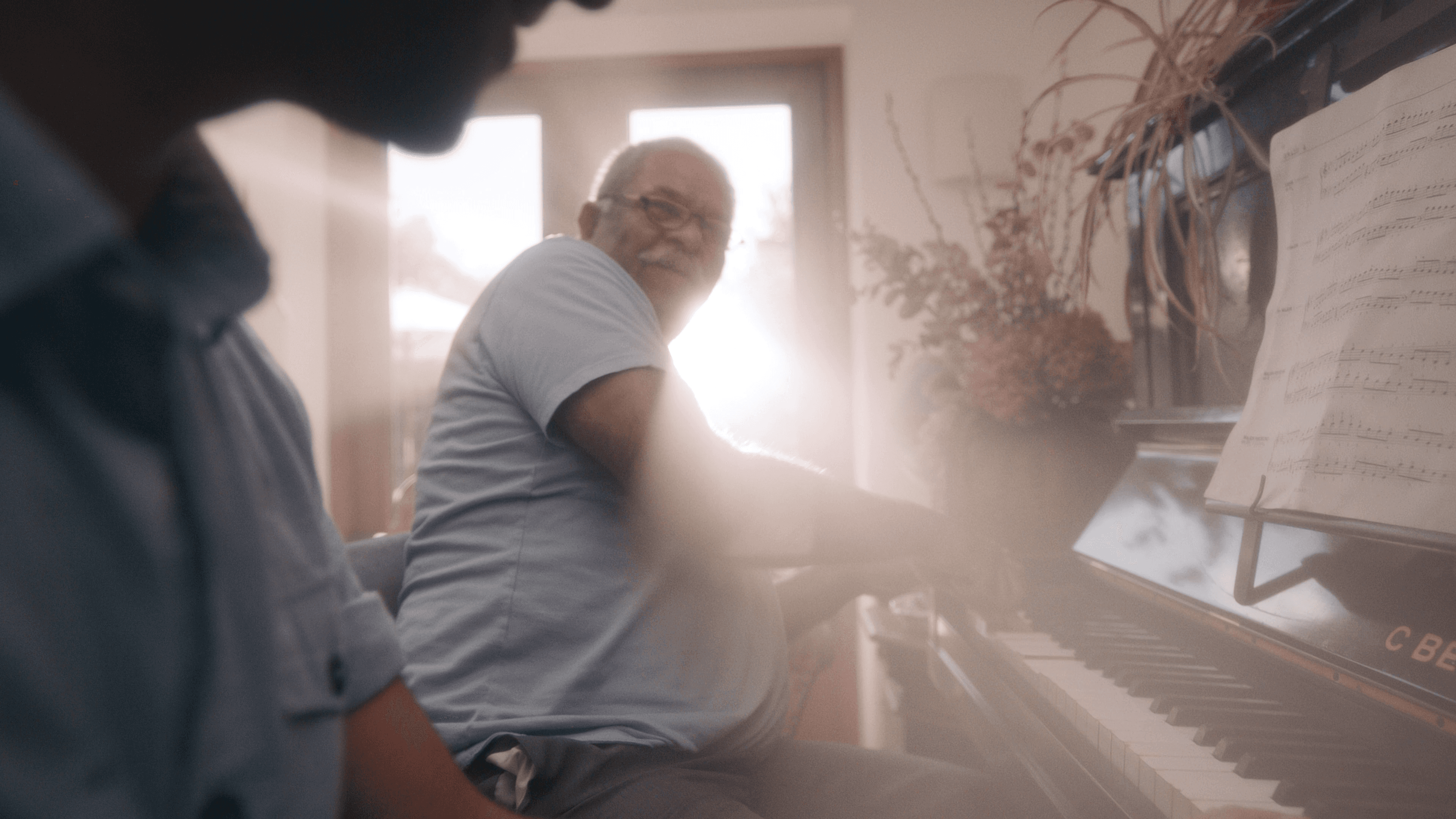 Two people playing the piano together, cinematically lit