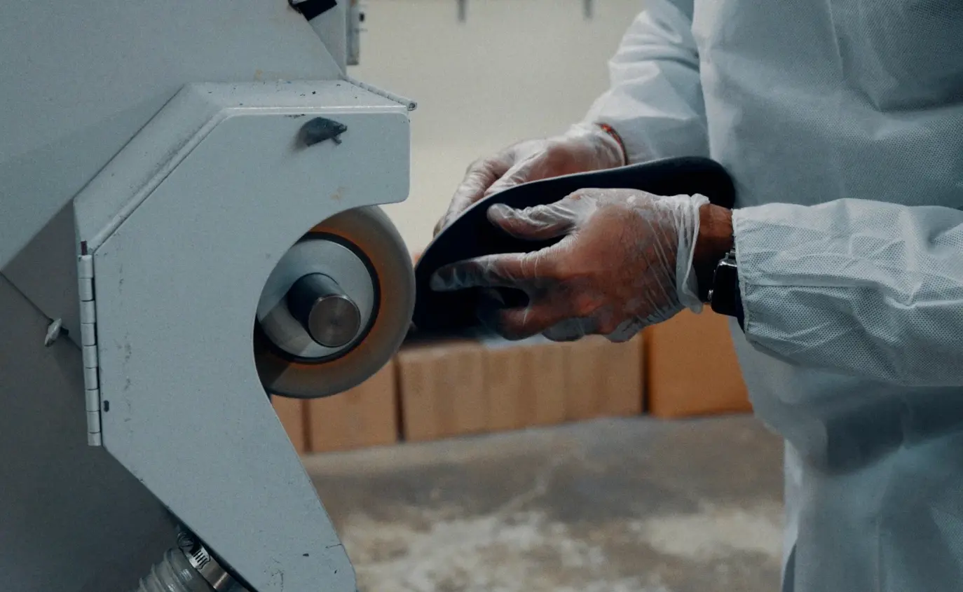 Gloved technician hand tightens a component on industrial equipment while filming-style preparation supports manufacturing video marketing workflows.