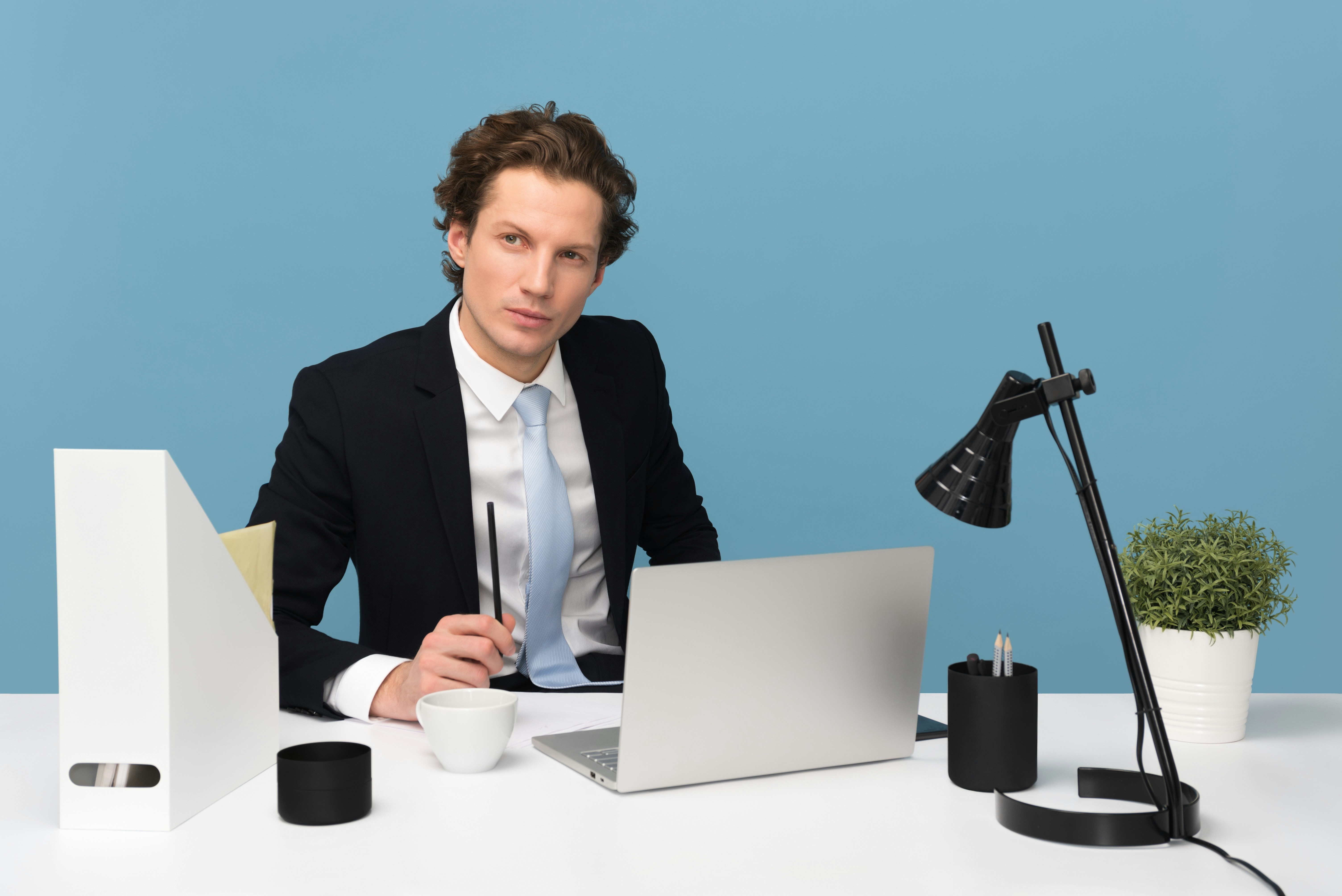 Mortgage broker sitting on chair beside laptop computer and teacup