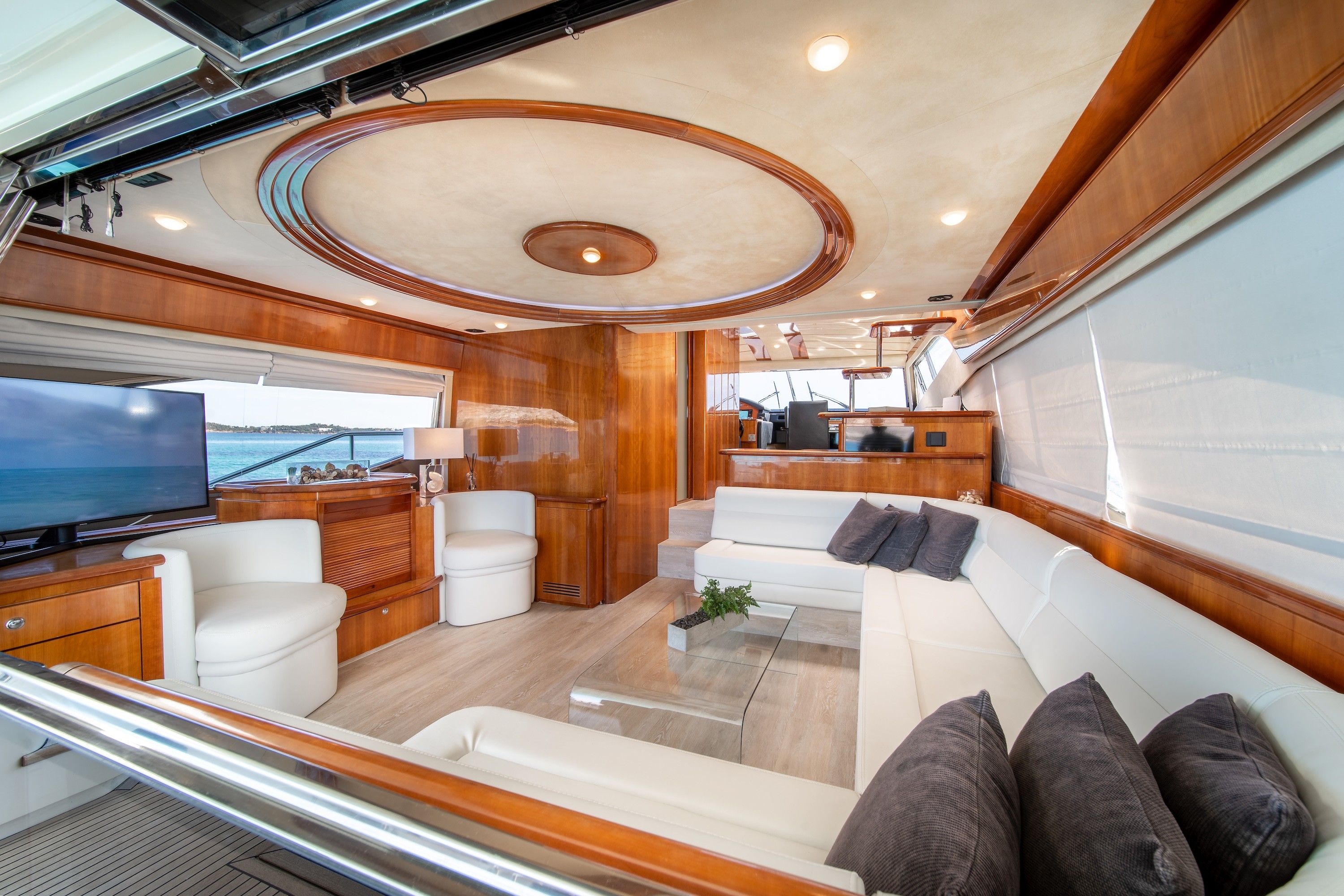 Luxurious interior salon of Ferretti 68 yacht featuring leather seating, glass coffee table, and panoramic windows with helm station visible.