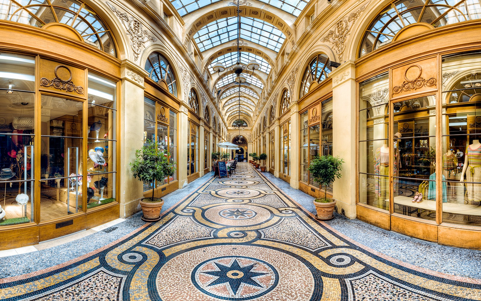 Passage couvert à Paris avec un plafond en verre orné et des boutiques.