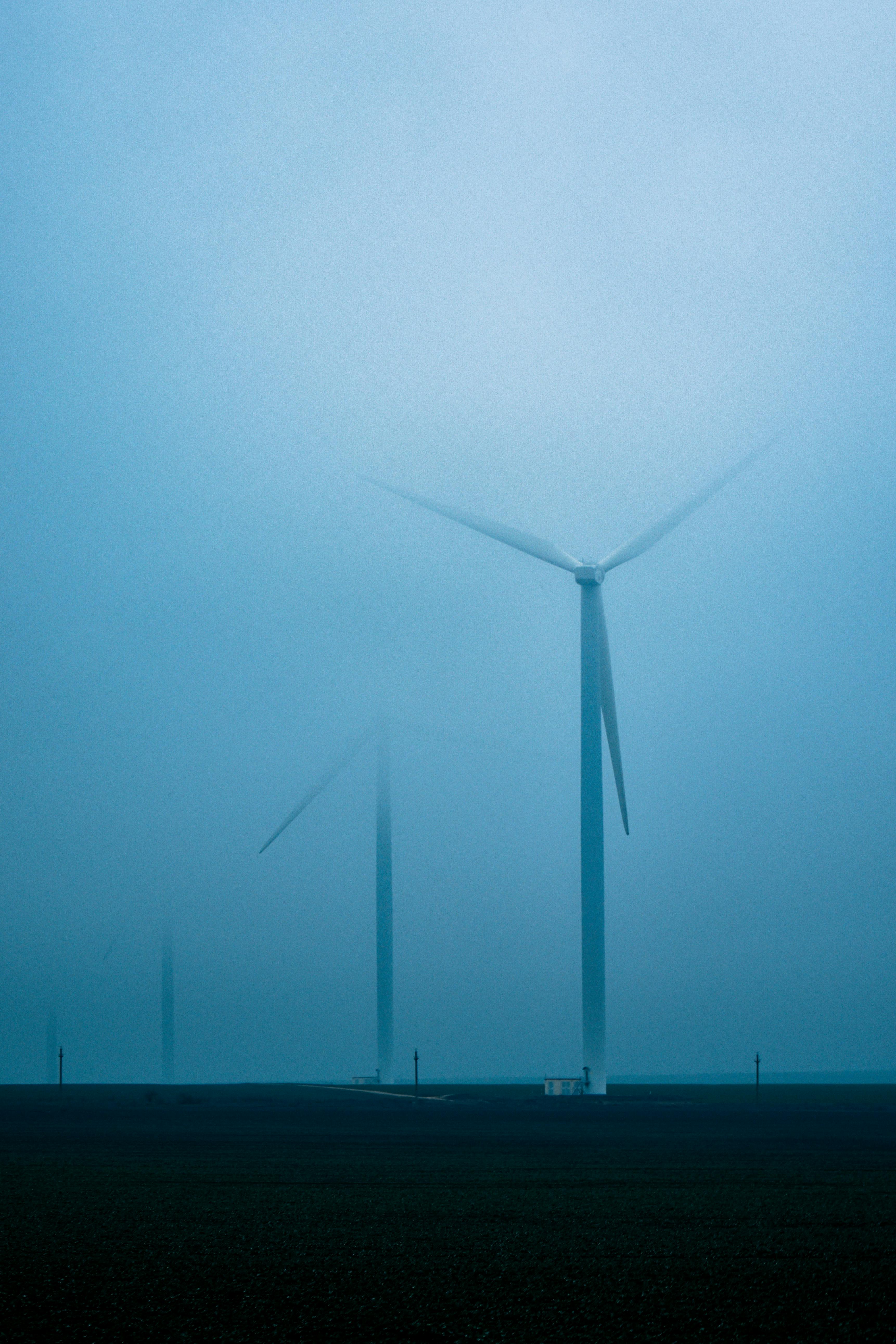 windmills near trees and body of water during day