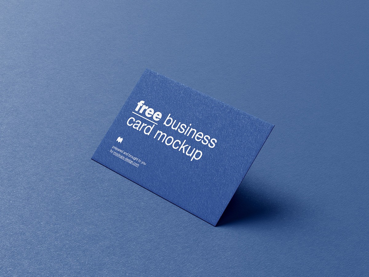 A blue business card with white text reading "free business card mockup." It stands on a matching blue surface, creating a professional and sleek tone.