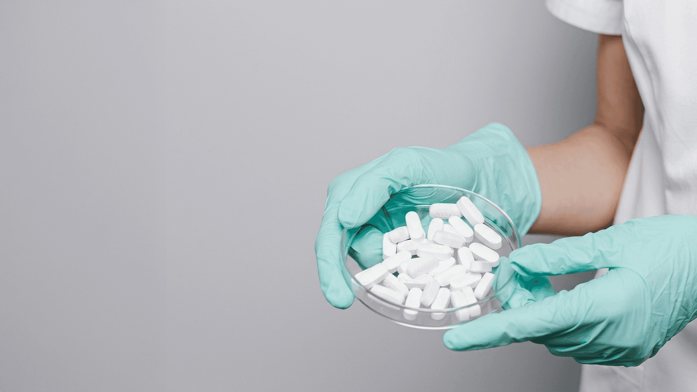 Tabletten in Schale mit Handschuhen