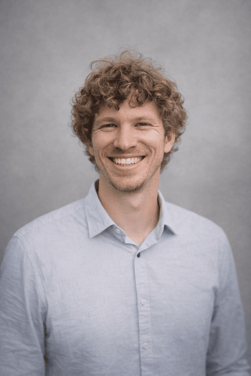 Black and white portrait of a smiling person with curly hair