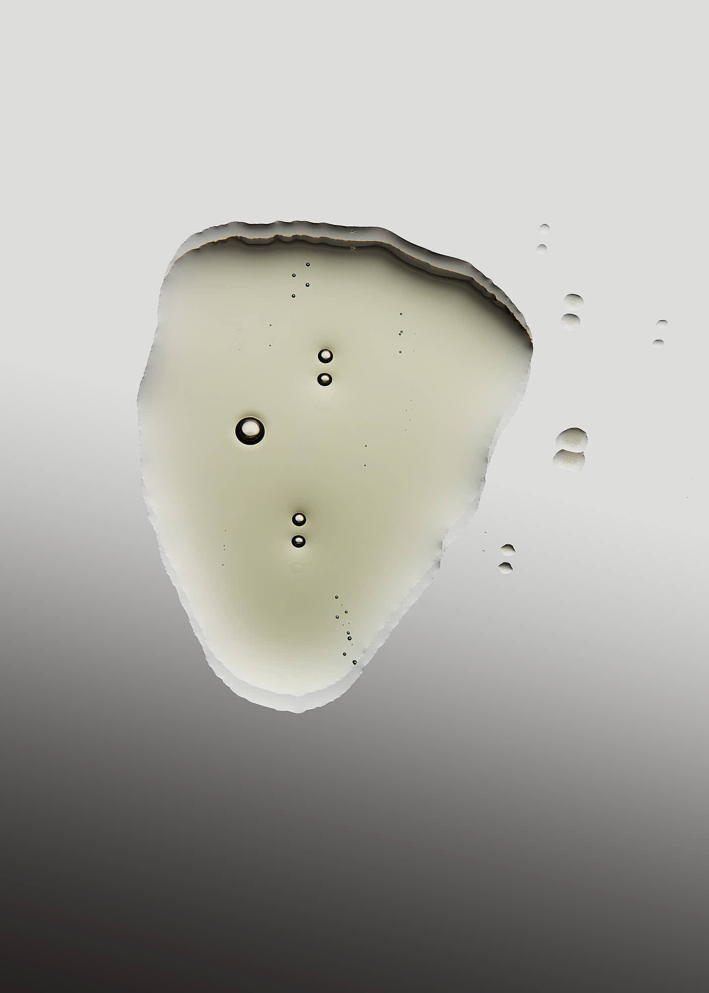 A close-up of a smooth, pale object shaped like a teardrop with small dark specks, set against a gradient background.