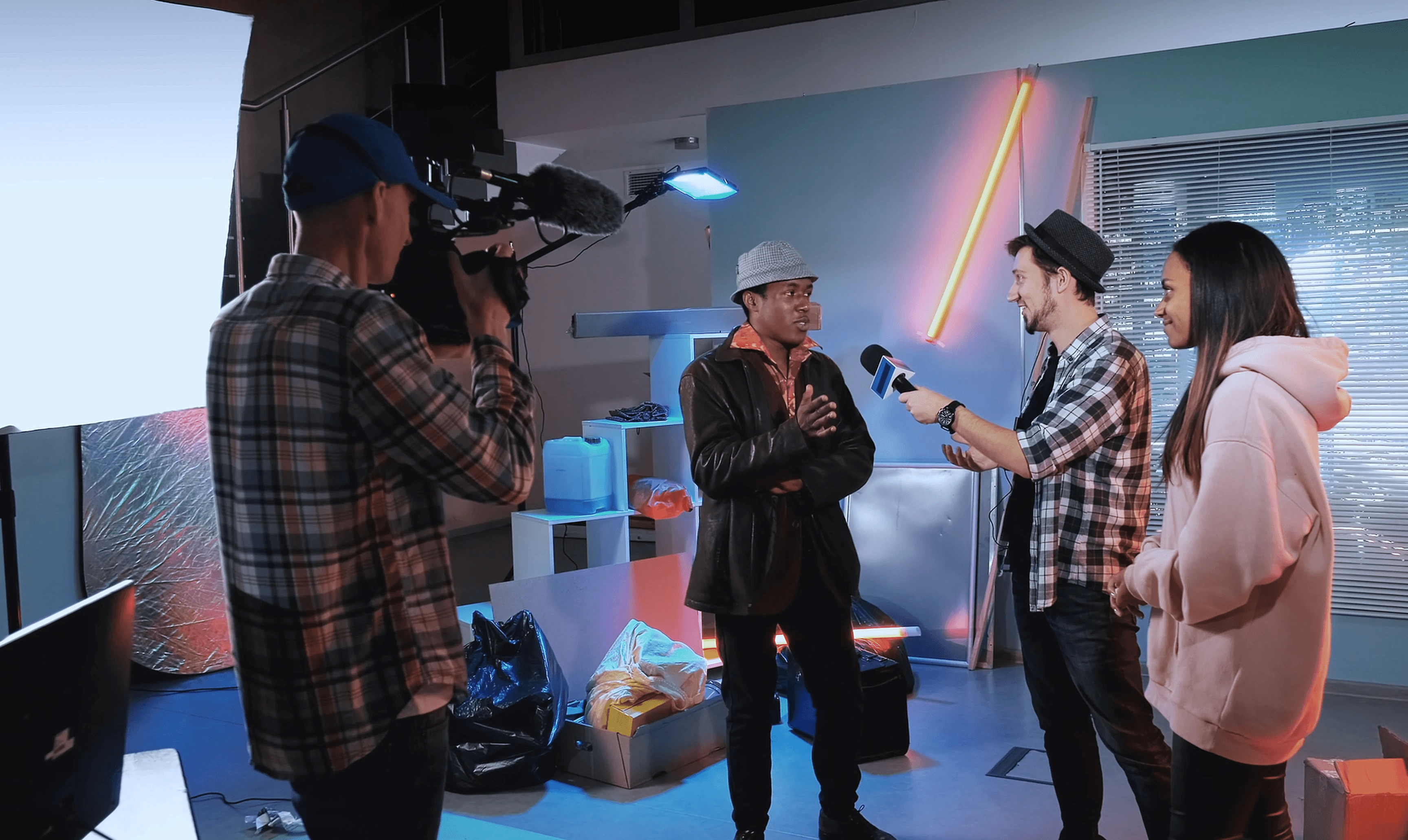 Creator team in a production studio — interviewer, camera operator and talent collaborating on a Playhuman Academy shoot