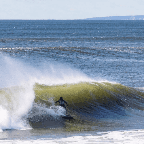 Surfer riding a wave on a sunny day – surfboard rental in rockaway