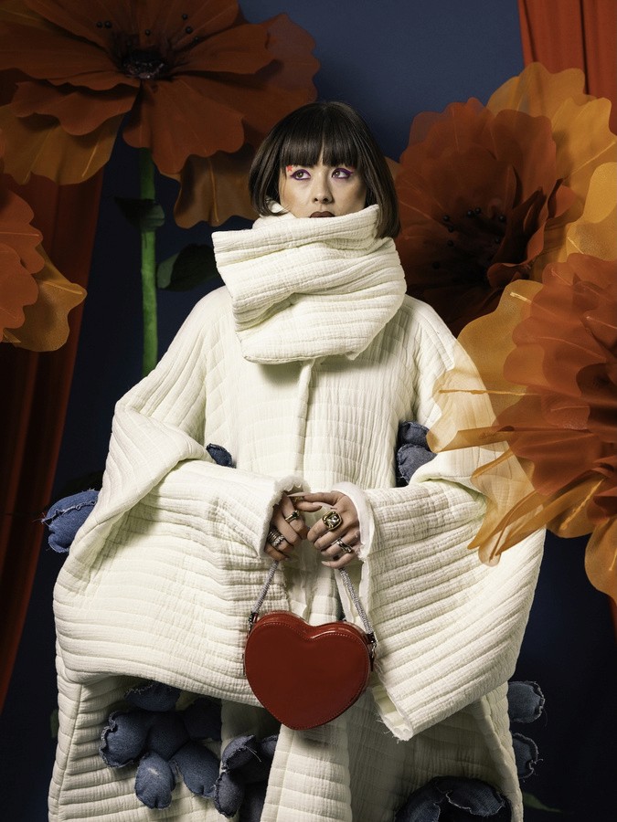 wearing a cardigan and psoing for a picture in a colorful background