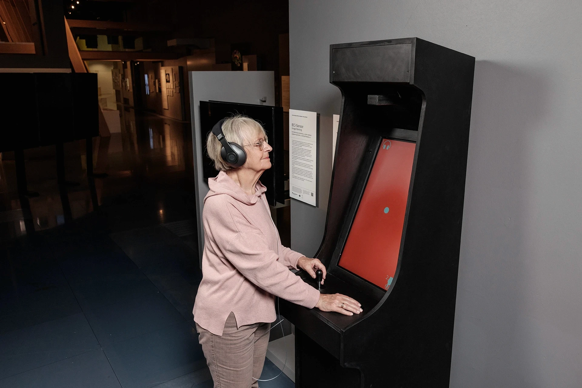 Woman wearing headphones plays an arcade game.