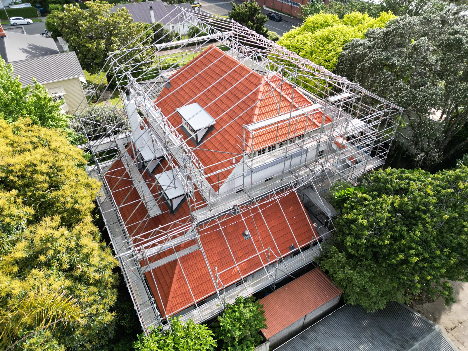 Red tiled house roof surrounded by scaffolding during a roofing project