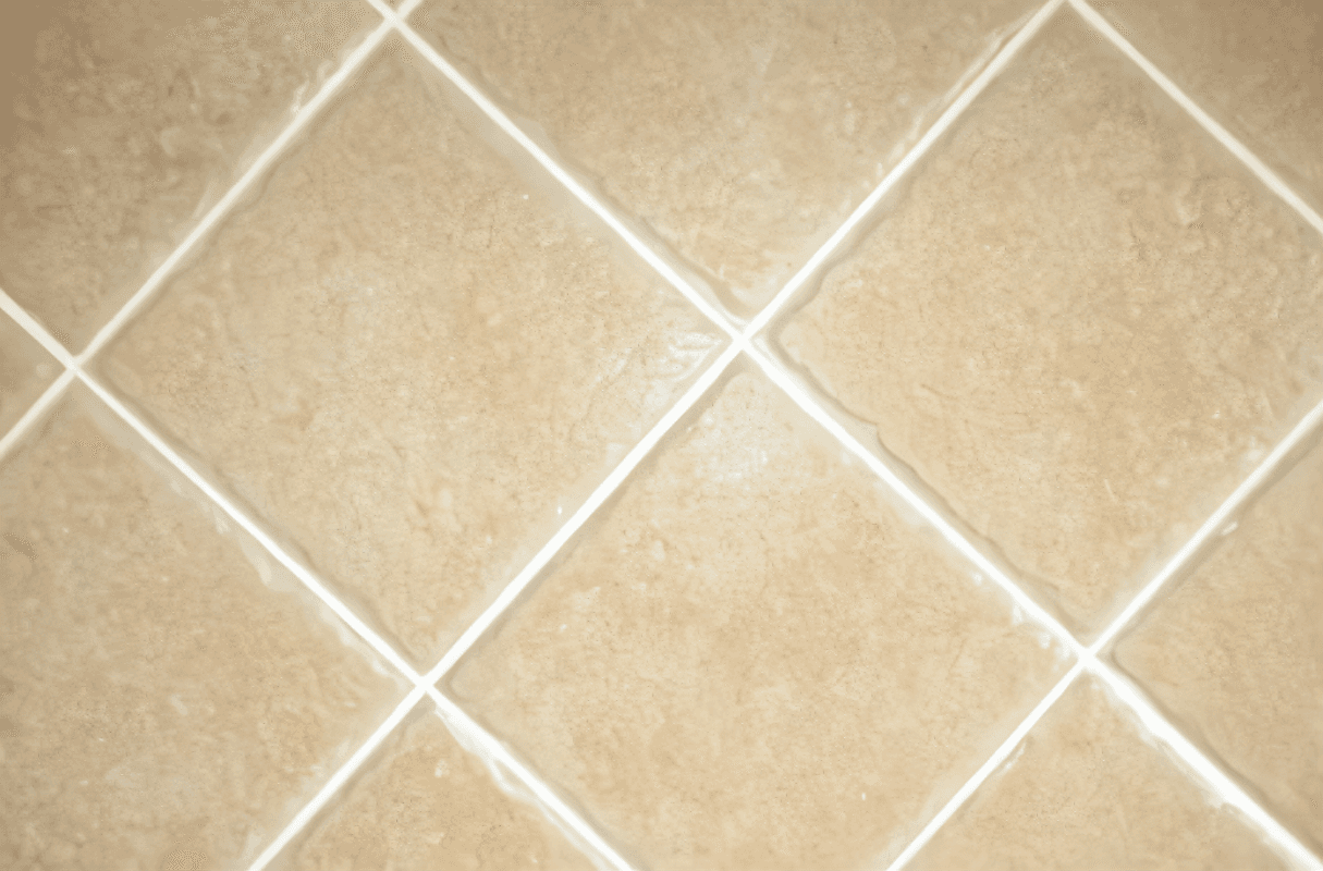 Beige ceramic tiles arranged in a diamond pattern with white tile grout neatly applied between each tile. The clean, consistent lines enhance the overall appearance of the tiled surface.