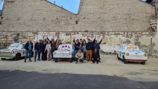 he Rhino.fi team posing in front of decorated cars during an outdoor team event