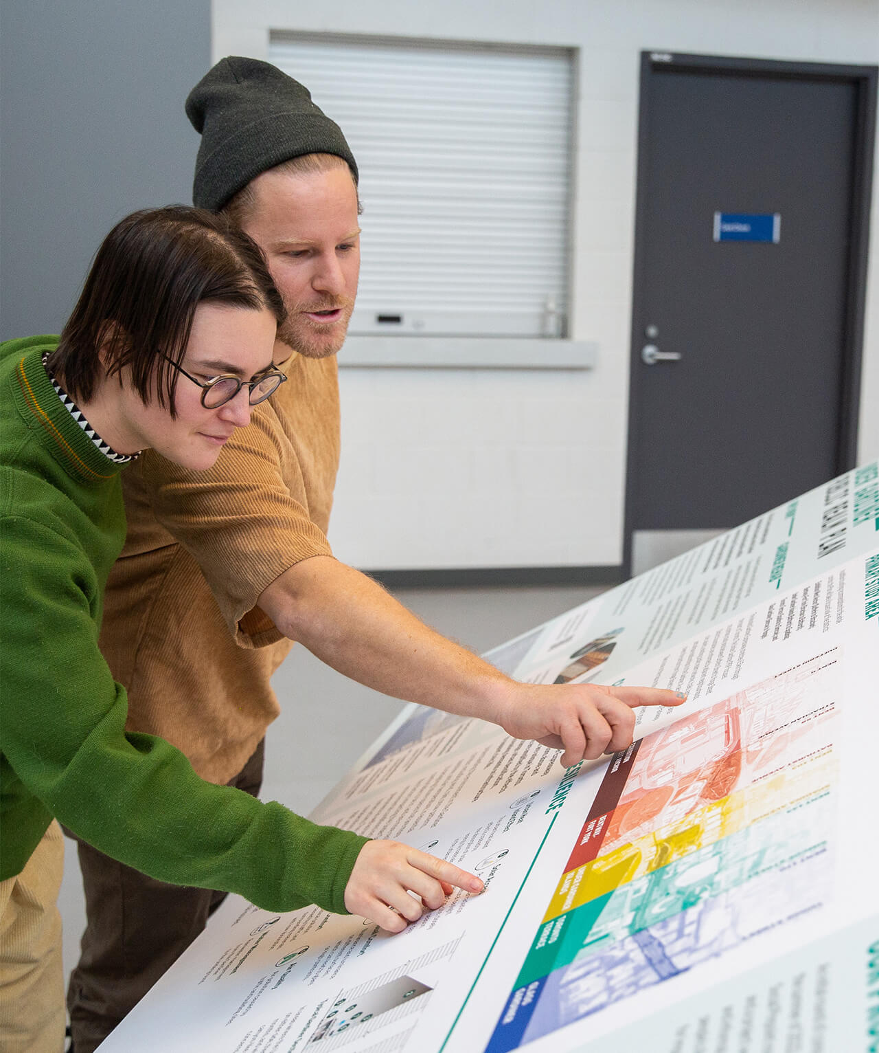 Two people pointing at a waist-height map of the Under Gardiner plan