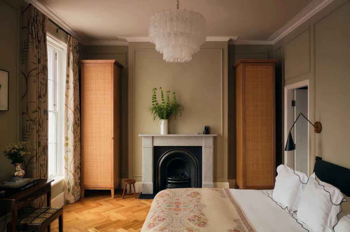 Masterful architectural bedroom suite in Kensington featuring a restored period fireplace, bespoke built-in wardrobes, and parquet flooring