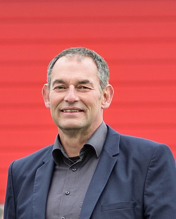 Portrait eines lächelnden Mannes in Anzug vor rotem Hintergrund. Führungskraft, Manager.