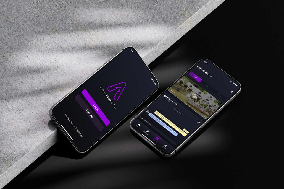 Two smartphones leaning on a sleek piece of stone showcasing a media app design