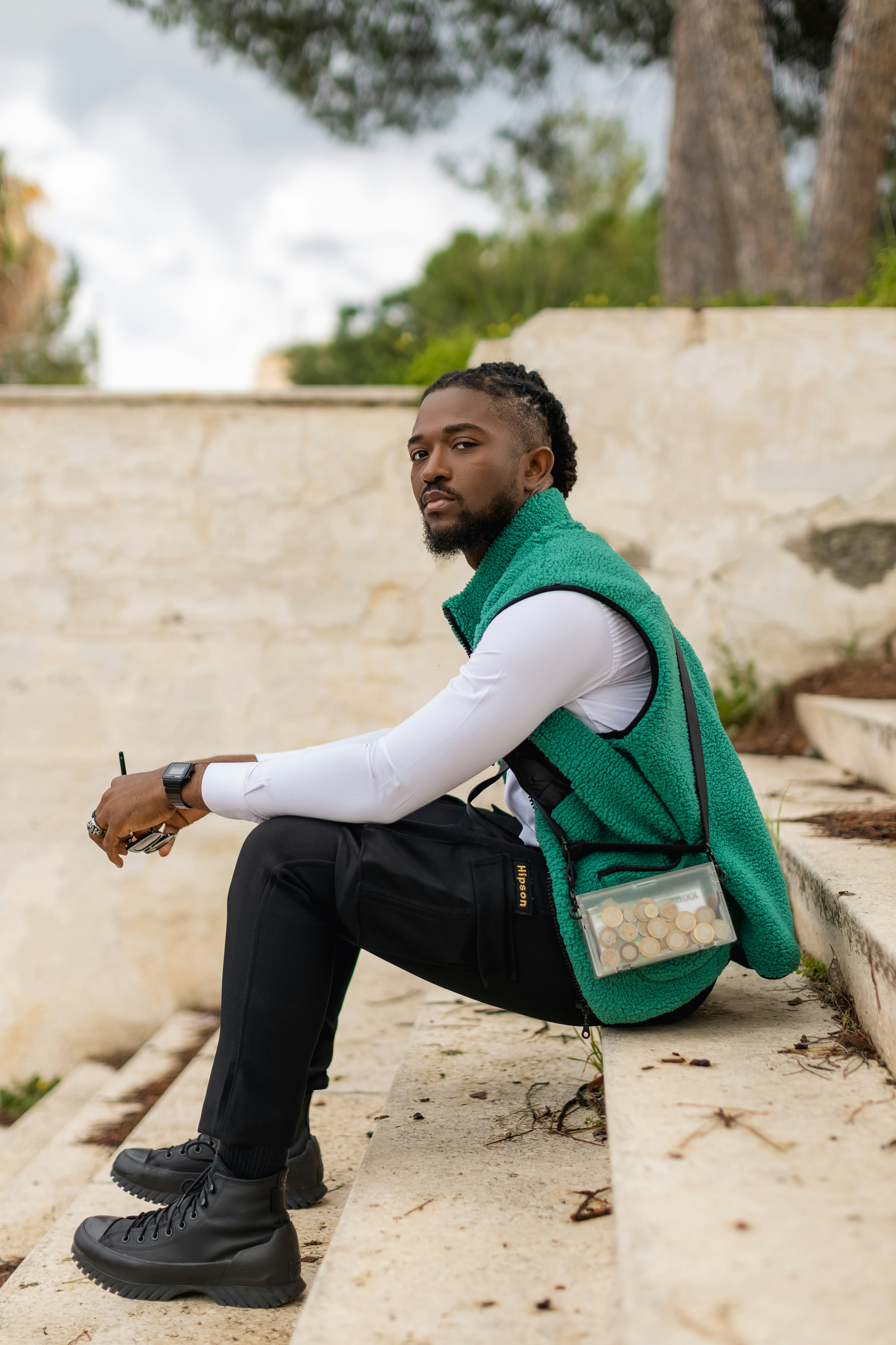 a man in a green vest sitting on a ledge