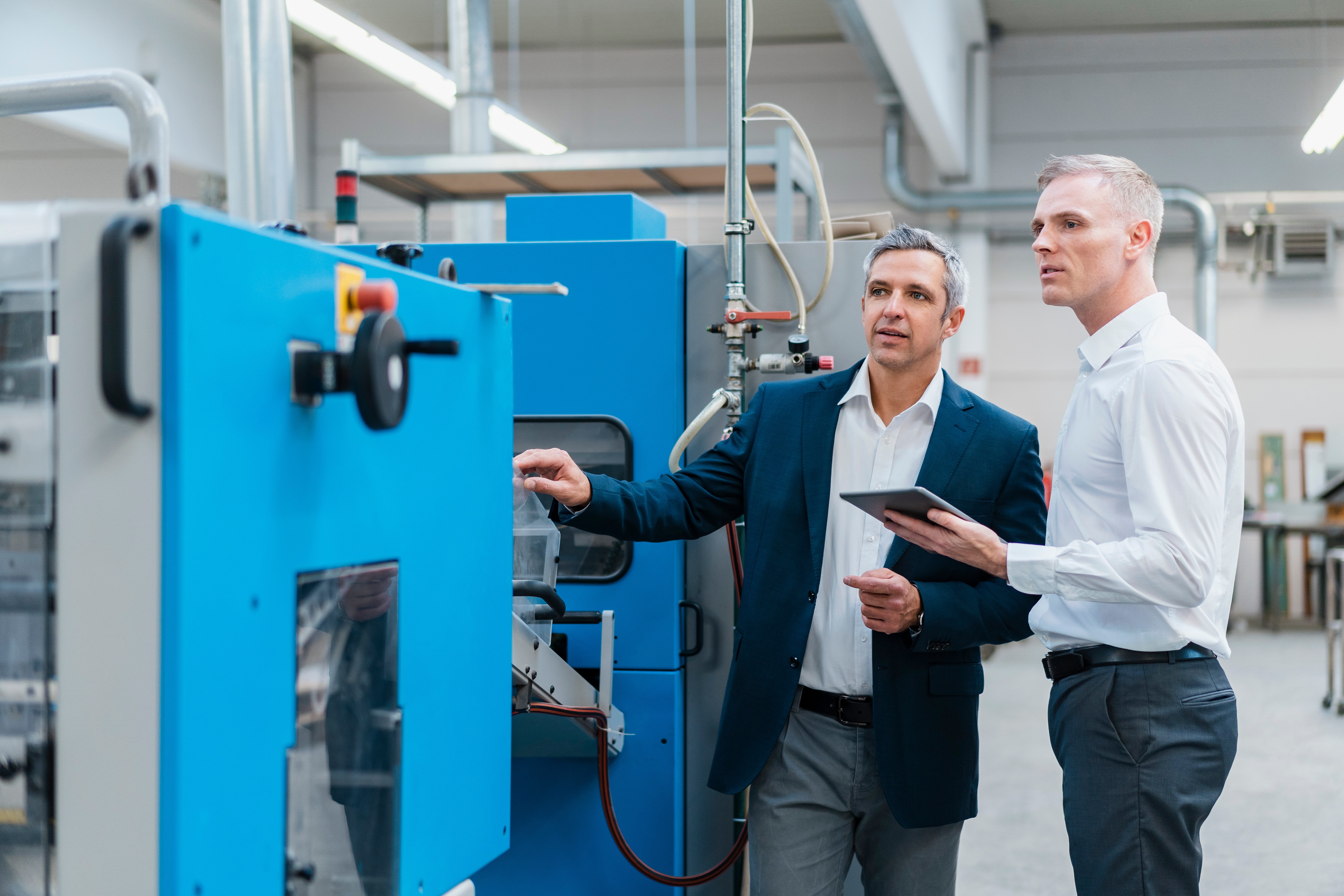 Auditor beobachtet einen Produktionsprozess und bespricht operative Steuerungsmassnahmen mit einer Produktionsleitung in der Fertigung