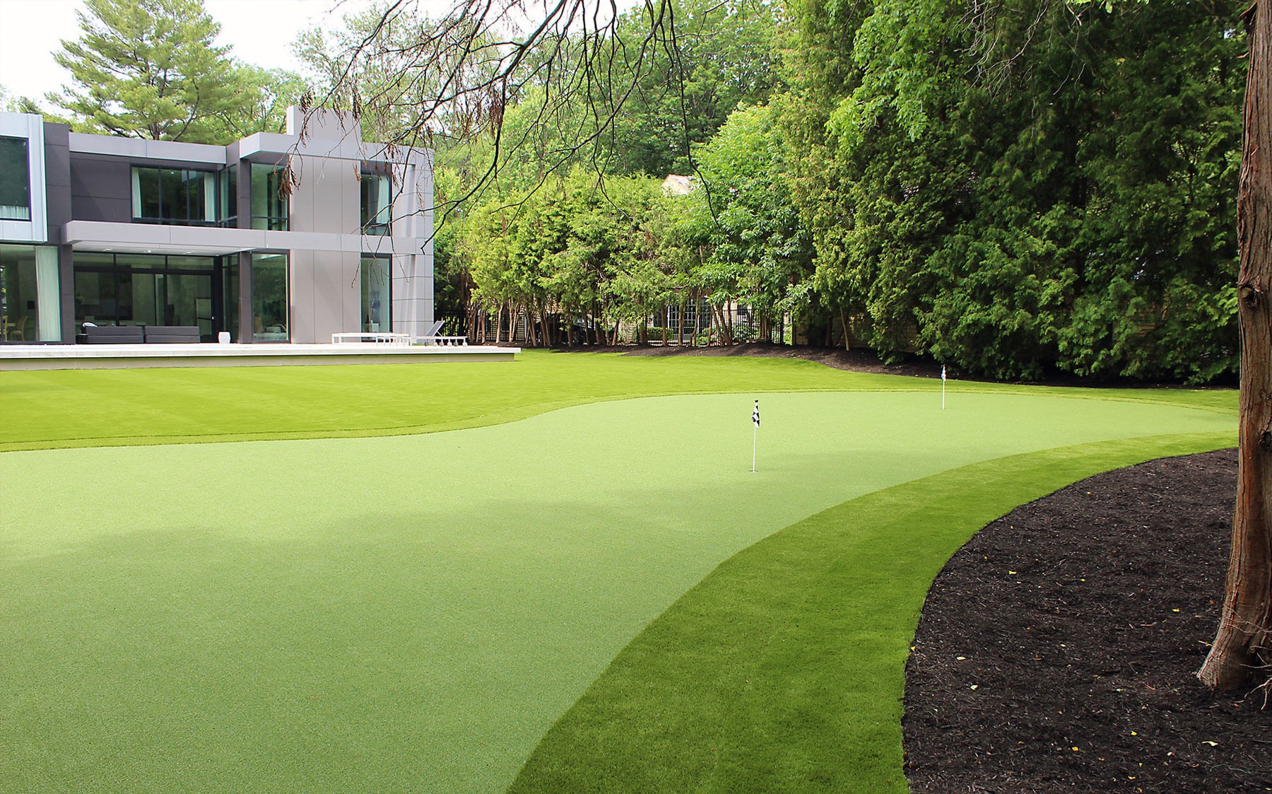 Brown bark contrasts the green Golf Leisure artificial putting turf by AGL Grass North.