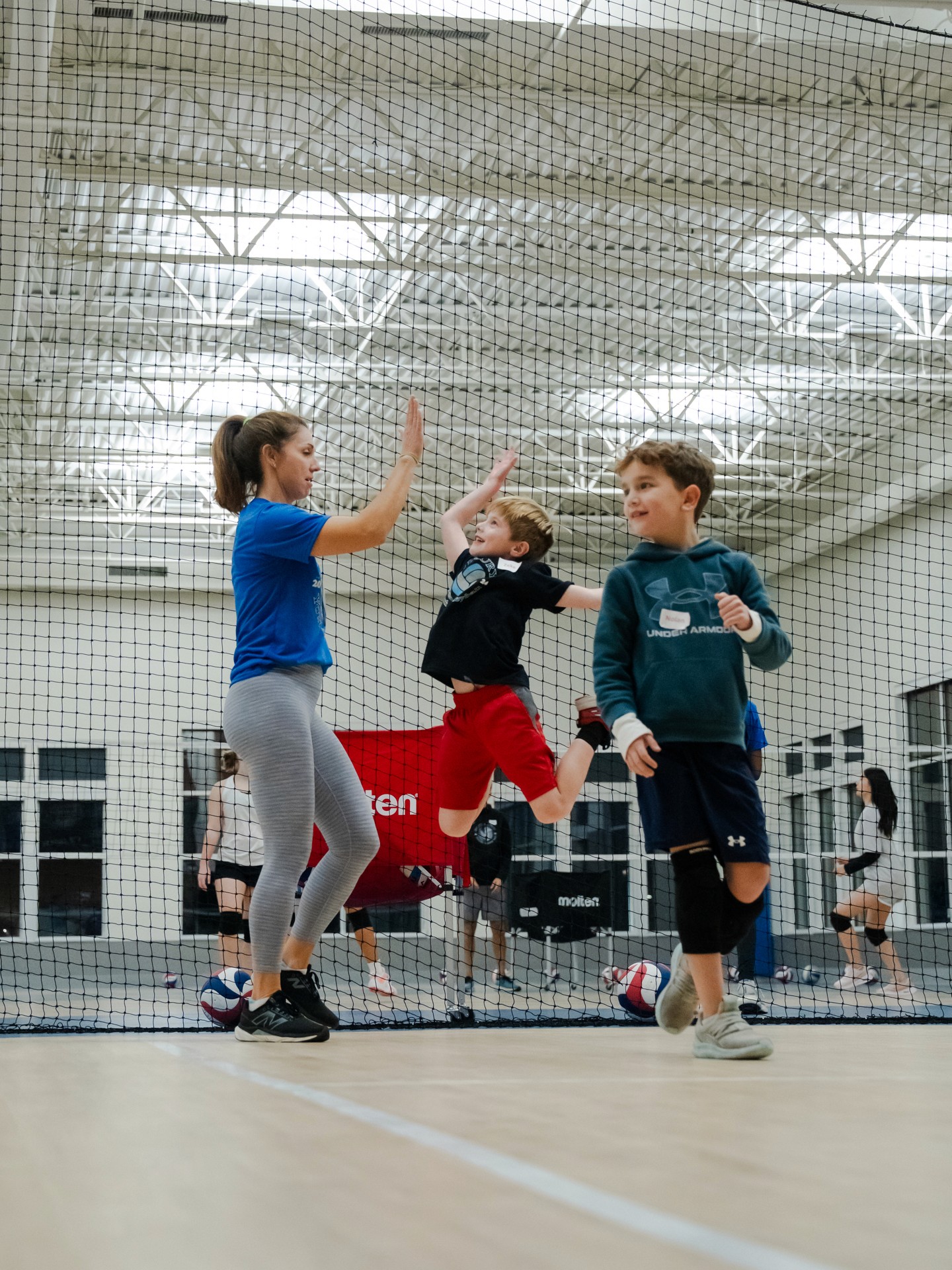 Kids high-fiving their coach at a Mini Volley practice