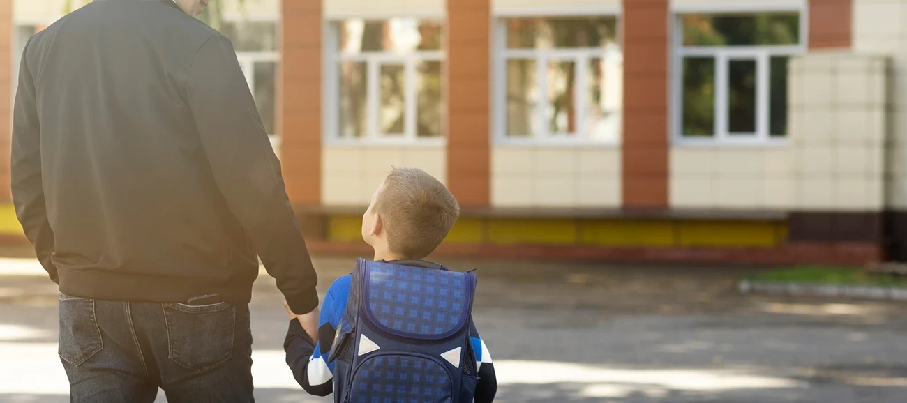 Père de famille avec son enfant devant l'école.
