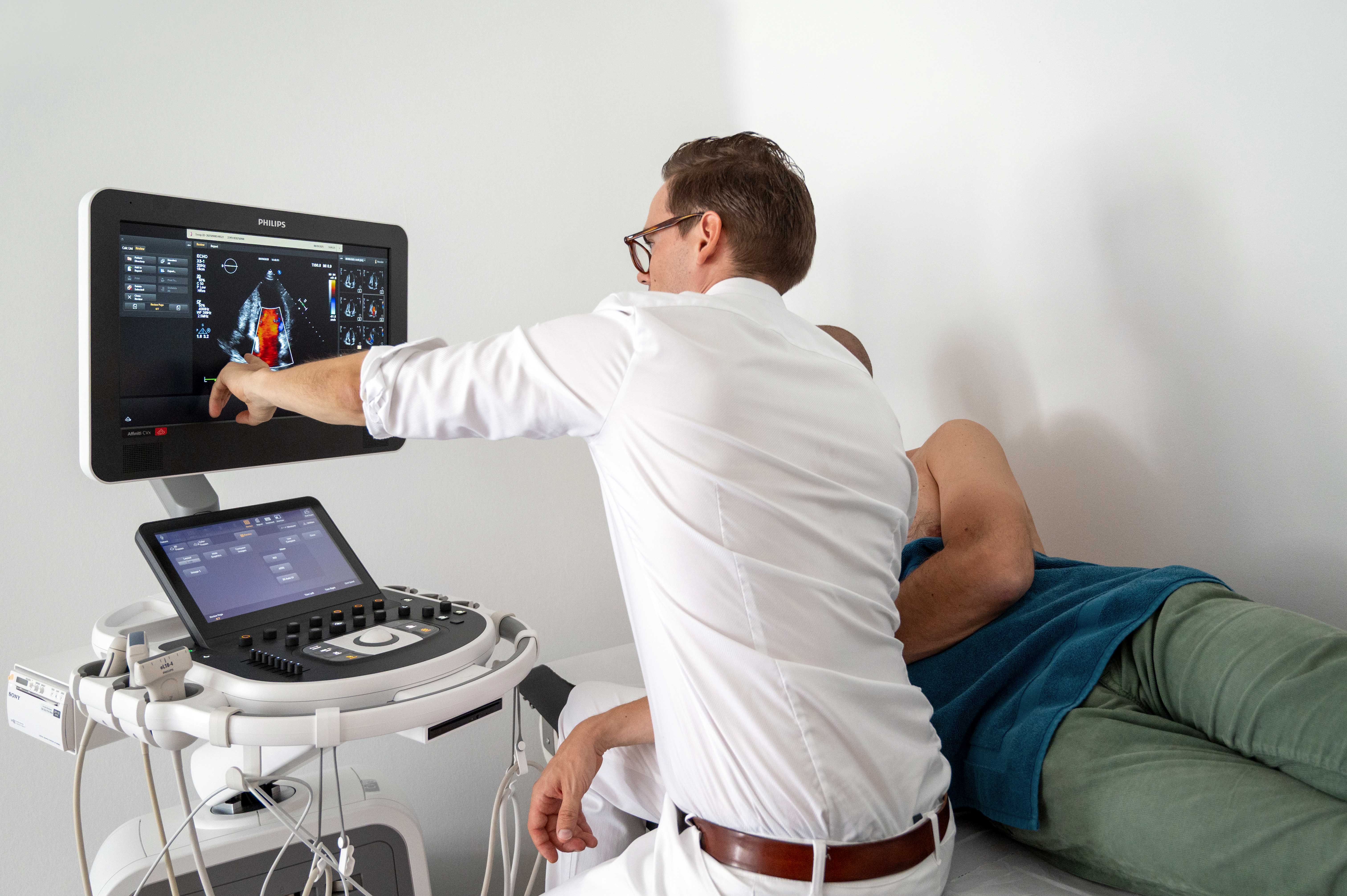 A male doctor examining a woman in an eye exam machine to assess their vision.