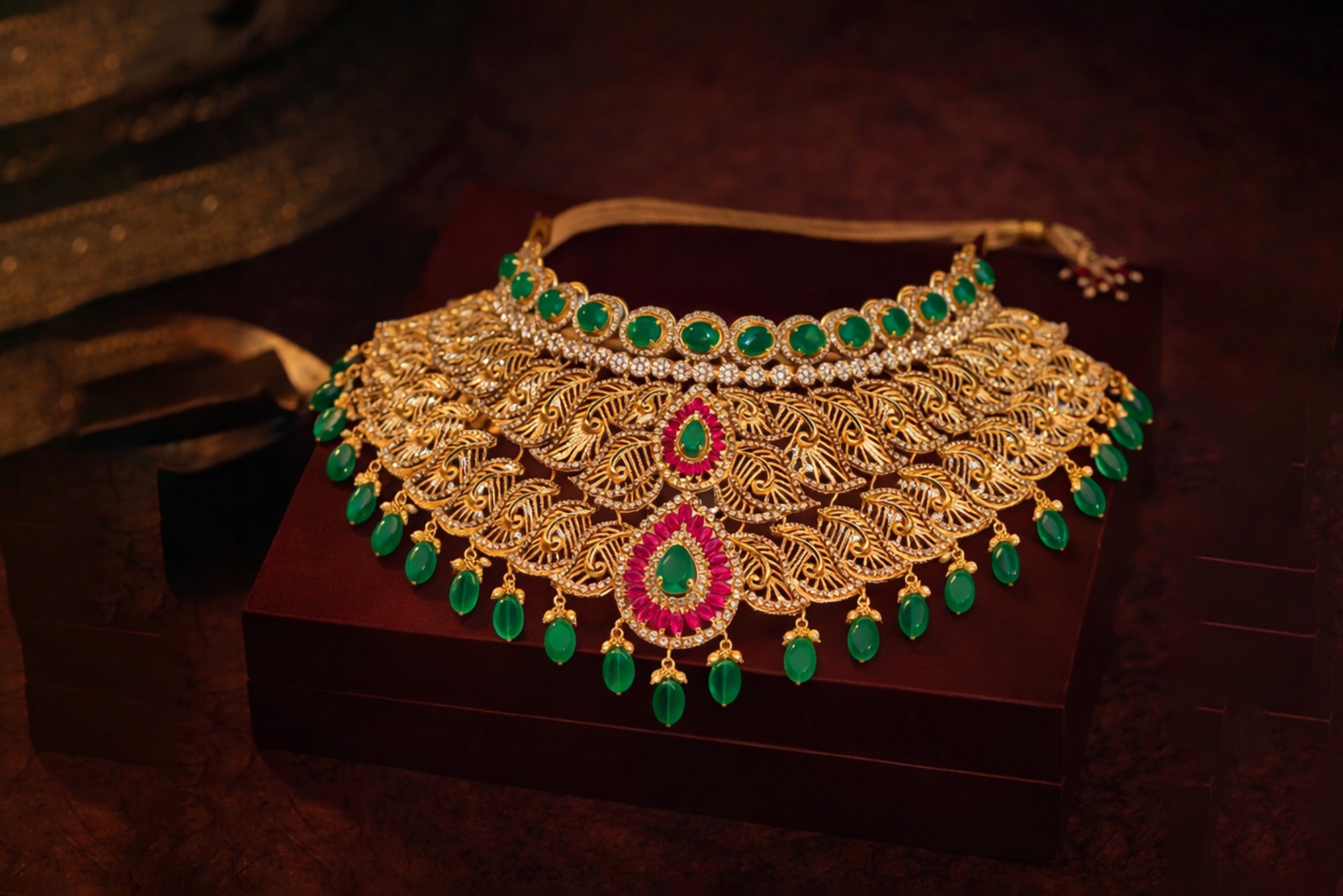 A person wearing layered gold necklaces, including a link chain and pendants, paired with thin gold rings.