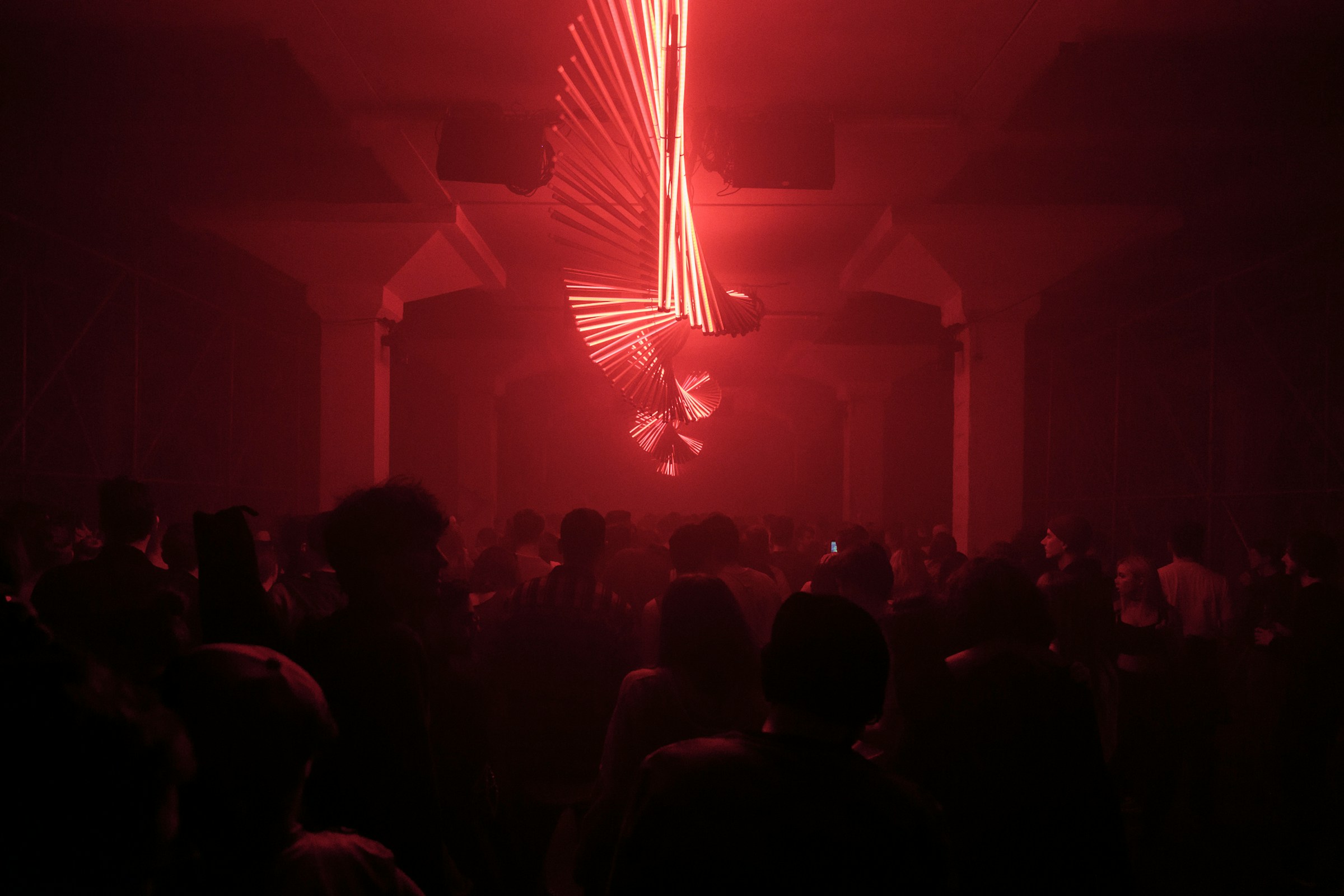 Crowd gathered in a red-lit electronic music space