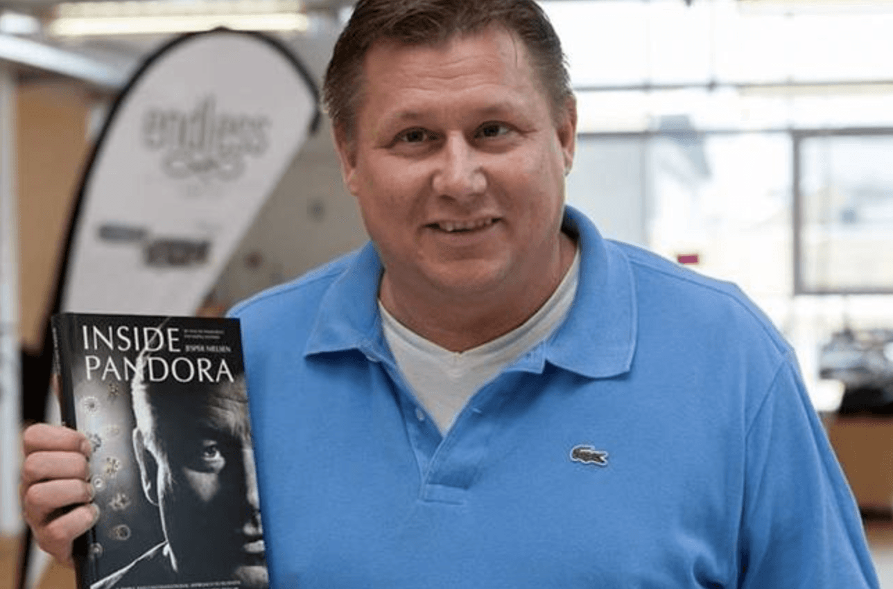 Focused man wearing a cap working on a laptop at a modern desk in a minimal office setting.