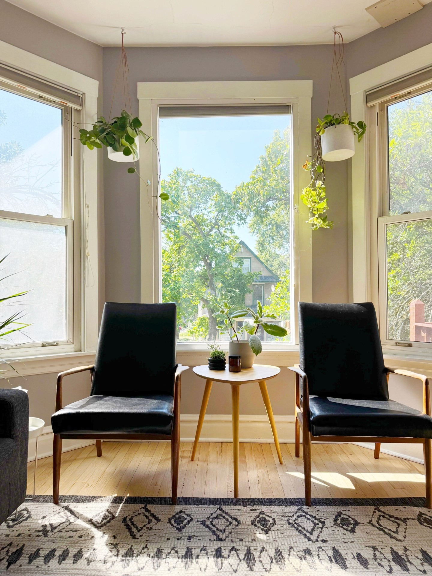 two black chairs in front of window with small round table and plants