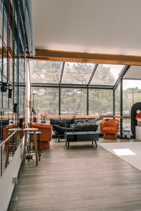 Bright studio interior with large windows and orange lounge chairs
