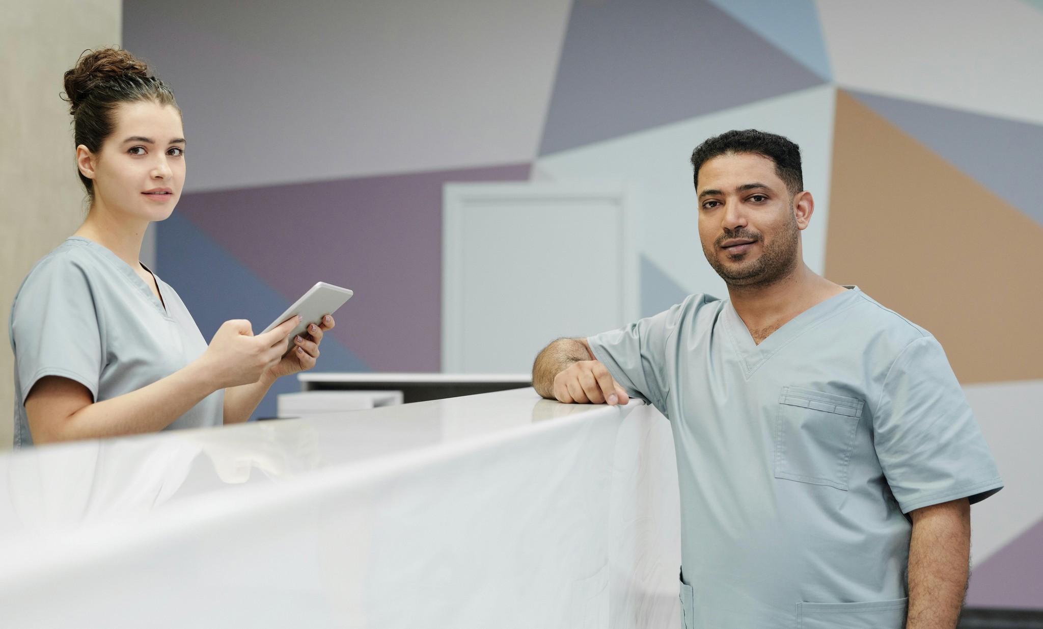 Two nurses chatting with each other, one behind a desk