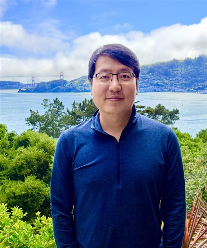 a man with his arms crossed standing in front of a desk