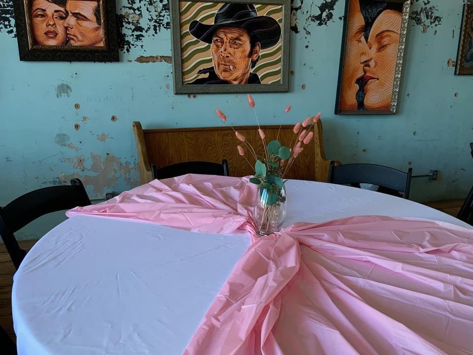 A table setting with a baby pink tablecloth at a baby shower taking place at Loose Latigo gallery