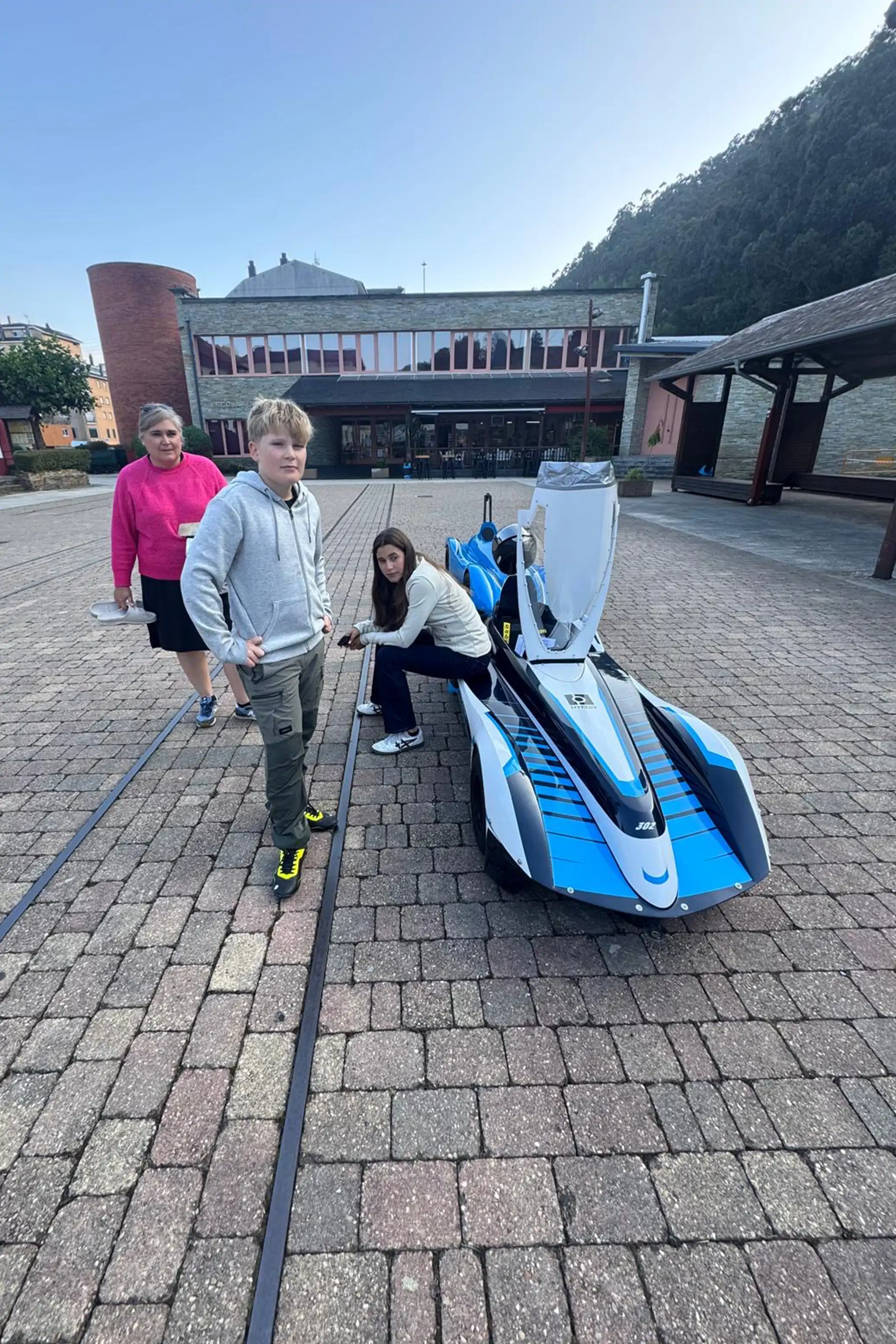 Famille poussant la caisse à savon Hypros sur une place de village