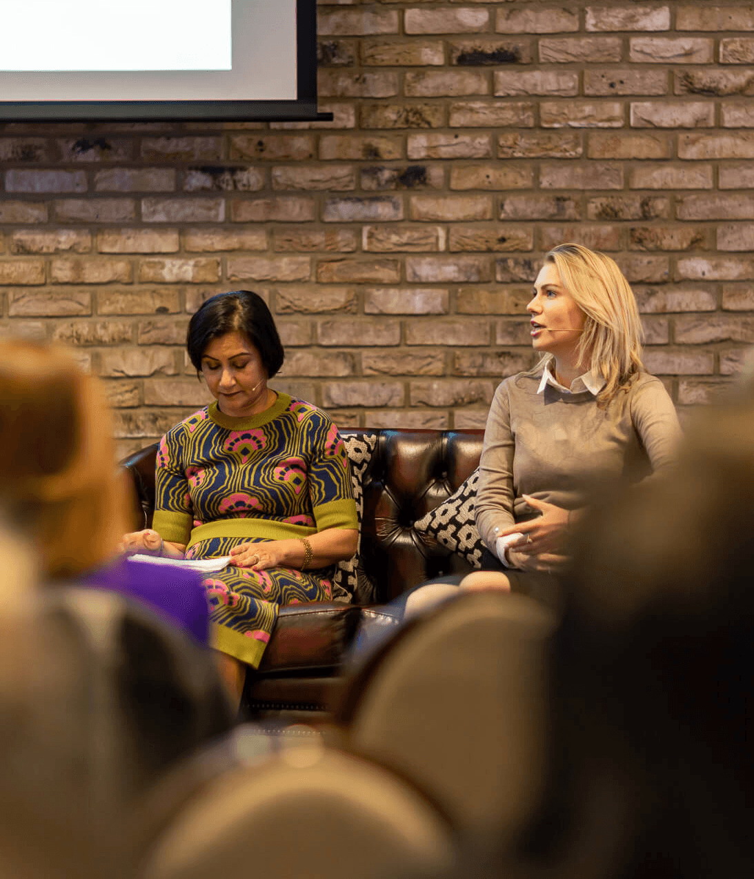 Women speaking during a finance event panel discussion in front of a live audience at a business conference